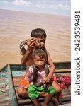 Small photo of Siem Reap,Camboda,July 6, 2019-A young boy and girl eke out a living for their family by getting tips from tourists along with their pet python on the Tonle Sap lake near Siem Reap,Cambodia