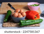 Small photo of Ingredients Pisto manchego (Manchego ratatouille) with red and green peppers, courgette, onion and eggs. Typical and traditional Spanish food. Horizontal photo and selective focus.