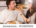 Girl feeds her husband with two slices of pizza. Exaggerate and wondering. Much credit on yourself and capabilities concept.