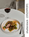 Small photo of Venison with a garnish of Belgian cabbage on the table with a glass of red wine and a fork with nod on the table