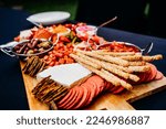 Small photo of Overhead view of a charcuterie board at an event with a blackred aesthetic. food is fresh and displayed on the board by a professional to be the most appealing.