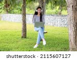 Lifestyle people girl working education on laptop and listening music for relax outdoor garden at home. Young asian woman sitting swing chill and resting in summer vacations