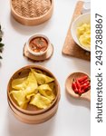 Small photo of Close up of dry Pangsit chili oil, Pangsit dower, or chili oil spicy dumplings served on bamboo steam, soup spoon, chili oil, and chili. Indonesian snack, jajanan viral. dry Pangsit for frozen food