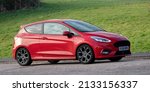 Small photo of Milton Keynes, Bucks, UK - March 6th 2022. 2018 998 cc red Ford Fiesta hatchback car travelling on an English country road