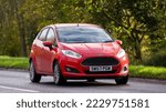 Small photo of Stony Stratford,Bucks,UK - November 20th 2022. 2013 red Ford Fiesta hatchback car travelling on an English country road