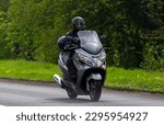 Small photo of Stony Stratford,Bucks,UK - April 30th 2023. Suzuki Burgman 400 Maxi-Scooter travelling on an English country road.