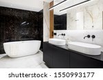 Luxury bathroom with dark and bright marble tiles and big bathtub