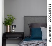 Small photo of Close-up on simple, black nightstand with decorations next to comfortable bed with stylish bedclothes