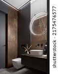 Small photo of Modern and elegant bathroom with toilet, small washbasin and rusty wall tiles and round, led lamp