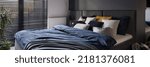 Small photo of Panorama of big and comfortable bed with stylish bedclothes in dark bedroom with big window with blinds