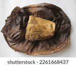 Small photo of Unrapped yellow corn local Ghanaian cooked corn dough meal wrapped with dried plantain leaves and boiled in water. it is known as (Fanti Kenkey)