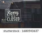 Vintage sorry we are closed sign hanging on a glass door.