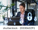 Small photo of Handsome businessman in suit at workplace working with laptop to defend customer cyber security. Concept of clients information protection and brainstorm. Padlock hologram over office background.