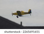 Small photo of North Little Rock, ArkansasUSA- April 28th 2022: A yellow dust cropper flying near houses in North Little Rock.