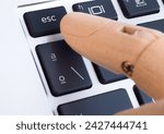Wooden finger pressing esc button on computer keyboard
