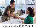 Young smiling army soldier meeting with his therapist and shaking hands while having a meeting at doctor