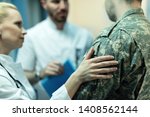 Close up of army soldier being consoled while talking with doctors at clinic. 