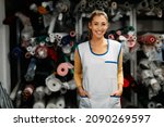 Small photo of Portrait of happy dressmaker working at clothing workshop and looking at camera.