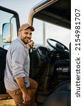 Small photo of Happy truck driver entering in vehicle cabin and looking at camera.