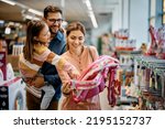 Little girl and her parents choosing backpack for school while shopping in the store together.