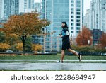 Side view of sportsman running while exercising in the park during rainy day. 