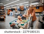 Senior couple going through shopping list while buying groceries in the supermarket. 