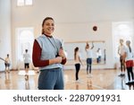 Small photo of Portrait of happy physical education teacher during a class at school gym.