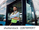 Small photo of Happy bus driver standing at the entrance of a vehicle with his arms crossed and looking at the camera. Copy space.