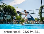 Small photo of Young athlete playing padel in mixed doubles on outdoor court. Copy space.
