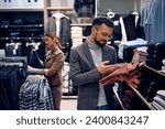 Young happy man buying clothes at shopping mall. 