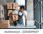 Small photo of Handsome business sme owners in apron with delivery box package stock warehouse preparing after received online order from customer in social media in laptop, he is influencer.