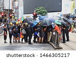 Small photo of CAUSEWAY BAY, HONG KONG - JULY 25, 2019: Protesters conceal their identity with umbrellas whilst they unbolt and remove pedestrian barriers in advance of Hong Kong protests.