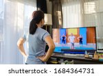 Small photo of Video streaming Stay home.home fitness workout class live streaming online.Asian woman doing strength training cardio aerobic dance exercises watching videos on a smart tv in the living room at home.