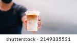 Small photo of Cold brewed iced latte coffee, Ice coffee latte cup in a plastic glass on. barista hand in coffee cafe.banner background.Cold brew coffee ads.Latte with milk caffeine.plastic ice cup.Arabica roasted.