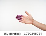 Small photo of Indoor photo of raised young woman's hand showing palm while posing over white background, having purple sparkles on it, going to shake somebody's hand