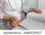 Hands of a female doctor holding a  medical journal in diagnostic cabinet. Doctor is waiting for patient. Stethoscope. Coronavirus.
