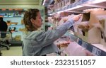 Small photo of Shopping woman select precooked pre-sliced meat product for breakfast sandwich. Female buyer among vast selection of stacked plastic packs in grocery discount retailer store. High quality photo
