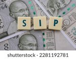 Small photo of Systematic Investment Plan or SIP in mutual funds, denoted by the words SIP written on tiles on backdrop of Indian Rupee notes.