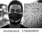 Young black man wearing face mask during equal rights protest - Concept of demonstrators on road for Black Lives Matter and I Can't Breathe campaign - Focus on eyes - Black and white editing