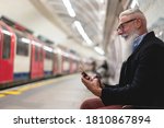 Hipster senior man chatting on his smartphone while waits for subway train - Mature man having fun with technology trends - Tech elderly joyful night concept - focus on face and hand