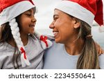 Mother and daughter having fun together during Christmas time wearing Santa Claus hats - Family and holidays concept - Main focus on mother face