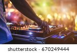 Dj mixing outdoor at beach party festival with crowd of people in background - Summer nightlife view of disco club outside - Soft focus on hand - Fun ,youth,entertainment and fest concept