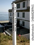 Small photo of Cabo Finistere Spain. May 2017. The lighthouse on the cliff edge. In the foreground is a with post with prosaic saying written on it in black. View of sea.