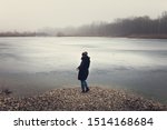 Sad and depressed looking Girl standing near a frozen lake 