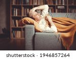An adult man lies on the couch at home against the background of a bookcase with symptoms of the disease.