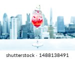 A glasse of pomegranate juice at the roof top bar on cityscape background. Raspberry and ice on a cityscape background.Selectived focus. Colorful cocktail to celebrate on happy relaxing cheerful day.