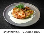 Chicken steak with vegetables in a ceramic plate on a dark textured background. Restaurant menu Isolated on black