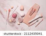 Makeup artist's tools in pink on a marble dressing table: brushes for powder, blush, eyebrows, shadows and sponges for concealer and foundation.