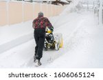 man operating snow blower to remove snow on driveway. Man using a snowblower. A man cleans snow from sidewalks with snowblower
