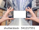 female holding a smartphone isolated blank screen with two hands on Abstract blur background of inside of warehouse with aisle pallet on high shelf, ready for snap a picture